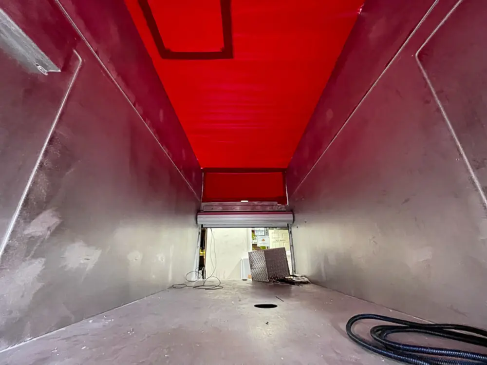 Exterior view of small fire truck showing cab, body compartments, and wheel/tire area.